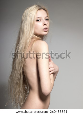 Young European attractive sexy fashion model with long blond natural hair, beautiful eyes, full lips, perfect skin is posing topless in studio for glamour vogue test photo shoot