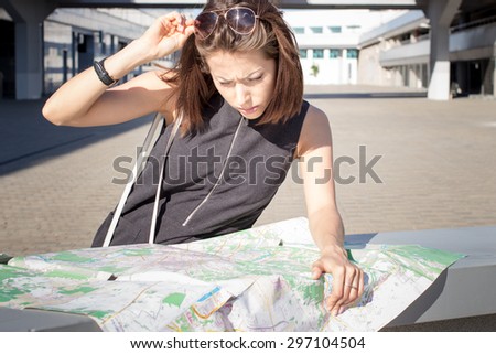 Attractive foreign female model looking on printed paper map in search of fastest directions to nearest hotel, restaurant, shopping center, main city square