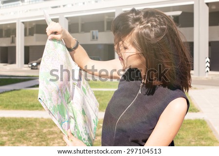 Attractive foreign female model looking on printed paper map in search of fastest directions to nearest hotel, restaurant, shopping center, main city square