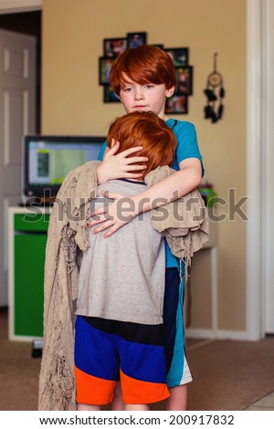 7 and 4 year old brothers hugging in their living room -- image taken in Reno, Nevada, USA