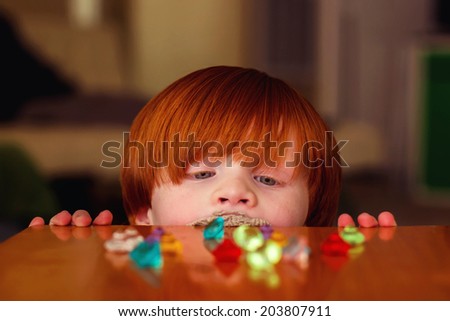 4 year old boy playing at a wooden table with toy gems -- image taken indoors in Reno, Nevada, USA
