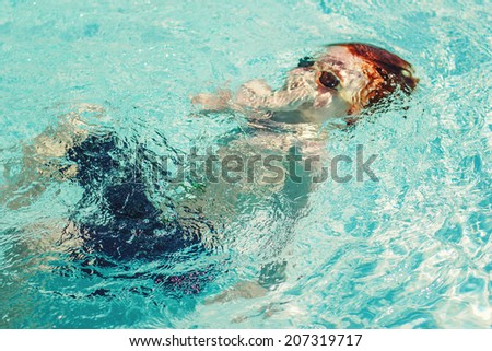 7 year old boy swimming in a pool on a hot summer day -- image taken outdoors in Reno, Nevada, USA