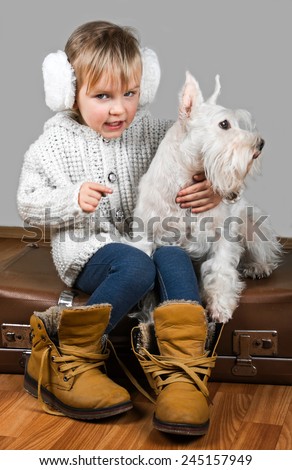 little girl sits on retro a suitcase with dog, ready to winter vacation.