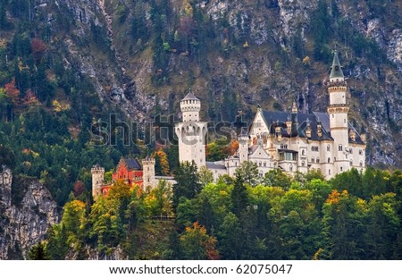 Dream castle Neuschwanstein of bavarian king in Germany, hanging on a cliff with a mountain in background, in autumnal light