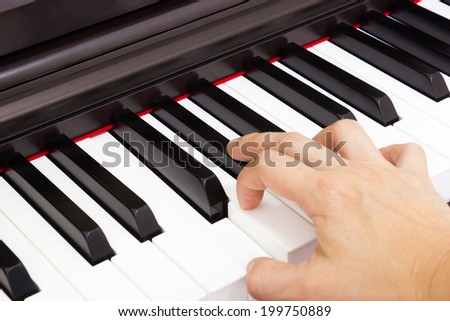 Closeup piano keyboard with women\'s hand on top view.