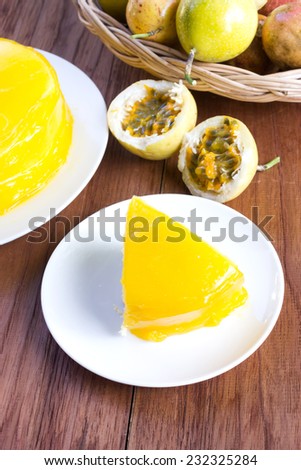 Passion fruit cake on white plate. Wooden background and fruit in a basket. Homemade cake.