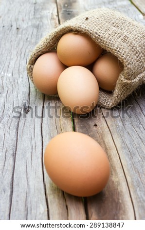 Egg in a small  burlap sack.  On wooden background. Selected focus on egg in bag.