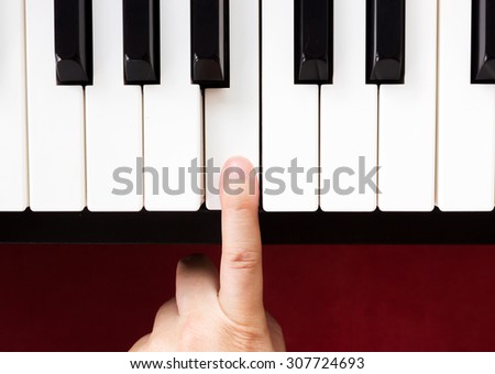 Closeup woman\'s finger pointing on piano key.