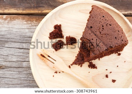 Chocolate cake on wooden plate with fork. On wooden table. Top view.