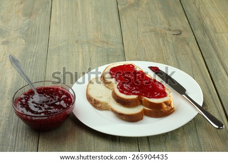 Toast with strawberry jam on a plate on a wooden background