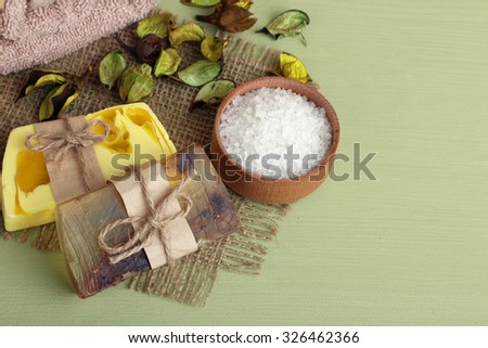 sea salt and soap next to the towel next to the leaves on a piece of fabric on a green background