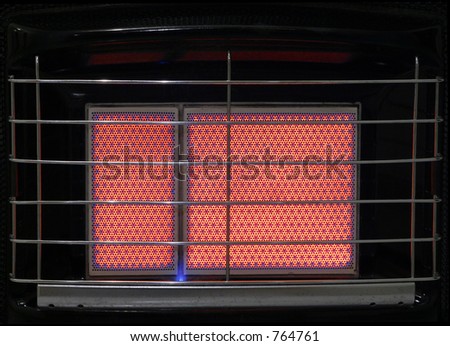 A close up of the heating ceramic of a switched on gas heater, with visible grill.