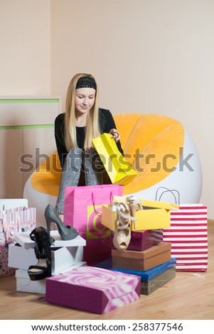 Young pretty woman sitting on a chair and looking into the bag. Woman on the shopping