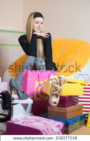 Young pretty woman sitting on a chair in shoes store and thinking. Woman on the shopping