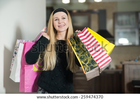 Pretty young woman holding shopping bags in the kitchen at home. Woman came home from the shopping