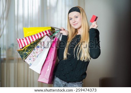 Pretty young woman holding shopping bags and credit card at home. Woman came home from the shopping