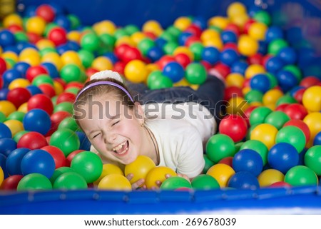 A girl in the playing room with many little colored balls. Close portrait