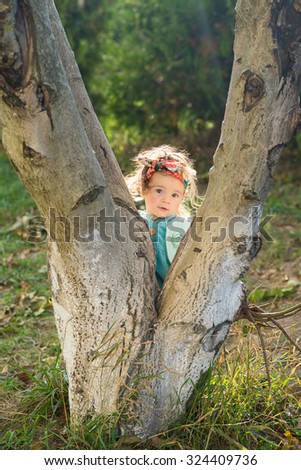 cute little girl looking behind the tree in the park