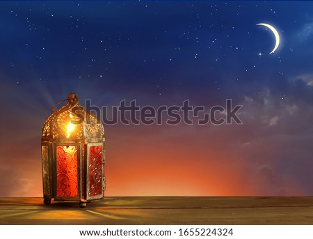 Islamic greeting Eid Mubarak cards for Muslim Holidays.Eid-Ul-Adha festival celebration.Arabic Ramadan Lantern on wooden table.Decoration lamp. Crescent moon and the stars. 