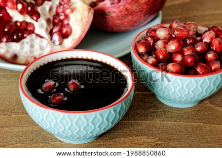 Pomegranate molasses in small bowl. Pomegranate sweet and sour syrup with pomegranate fruit and seeds.