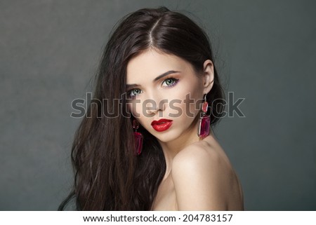 Beautiful woman with bright makeup and long brown hair wearing fine jewelry