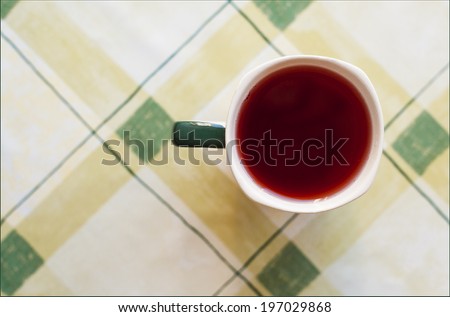 red juice in a ceramic mug on a table cloth with a green cell. top view
