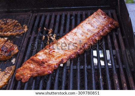 Grilling pork ribs and pork neck, on a barbeque