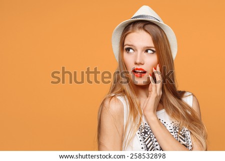Surprised happy beautiful woman looking sideways in excitement. Isolated over orange background