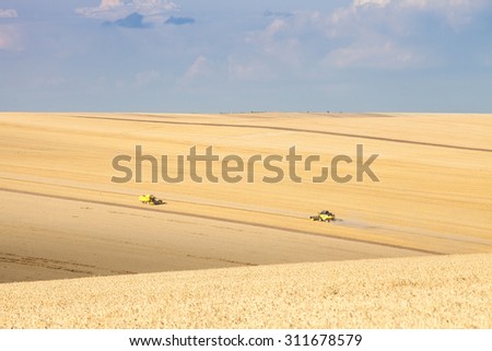 Svishtov - July 3: combine harvests wheat against the blue sky with white clouds on July 3, 2015 Svishtov, Bulgaria