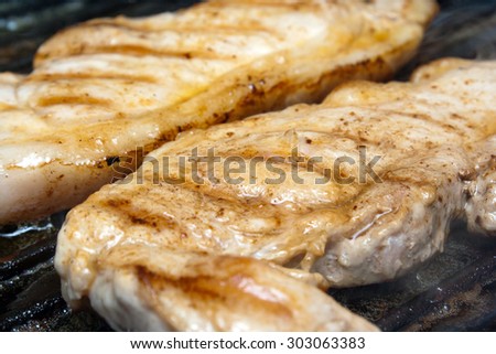 Pork fillet steaks close up frying in a griddle pan