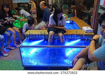 BANGKOK - 1 May 2015 : fish spa at Asiatique The Riverfront. Fish spa treatment basically involves customers placing their feet into a water tank filled with toothless garra rufa fish .