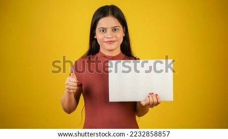 Beautiful young woman holding empty blank white board doing thumbs up, your text here concept, Asian Indian girl isolated over colour background studio 商業照片 © 