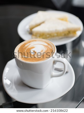 cup of coffee and sandwich on glass table