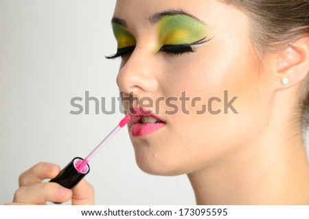 Portrait of young Polish female. Teenage girl with colorful makeup using lip gloss on her lips.