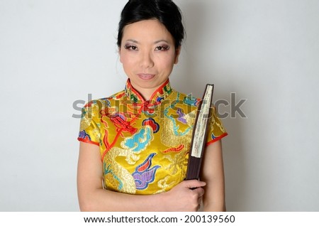Elegant Chinese lady wearing traditional colorful dress. Kind female model from Asia holding fan in her hand.