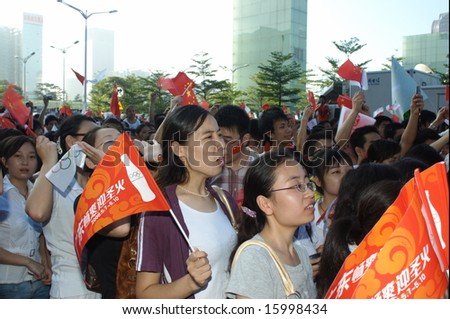 Chinese people, gathering and cheering, holding national flags, sport\'s fans. Happy and proud of Beijing Olympic 2008.