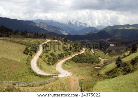 Beautiful landscape in Yunnan province, China. Country roads, hills and high Sino-Tibetan Mountains.