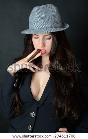 Girl with tail-coat and hat. Female model holding cigar, confident brunette.