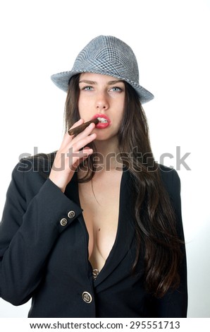 Young female model with confident face expression.Girl holds cigar in her mouth, wears dark tail-coat and hat.