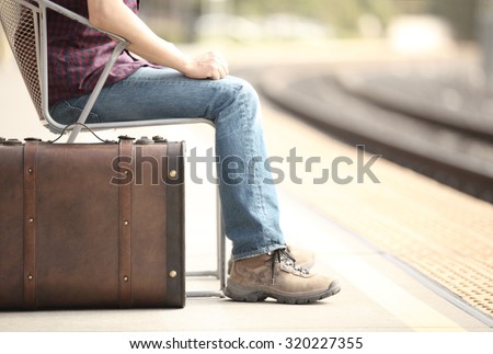 Casual traveler tourist waiting in a train station with a retro suitcase.