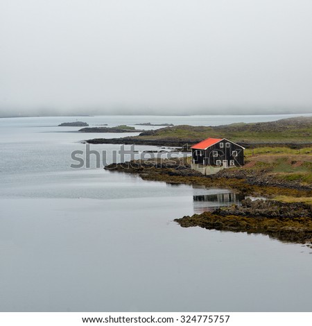 Lonely house at coastline in East Iceland, foggy day.