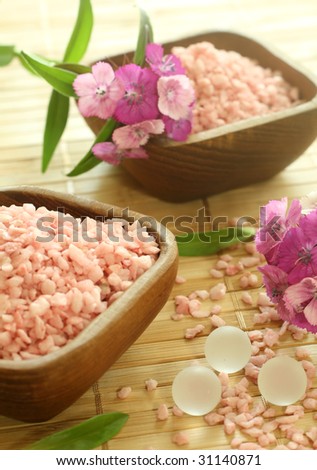 Spa essentials. Pink bath salts in wooden bowls and flowers.