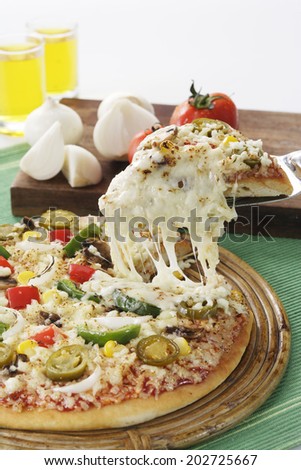 Pizza with lifted slice surrounded by vegetables