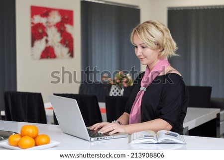 Blonde woman in black dress is working on a laptop in the bench top.