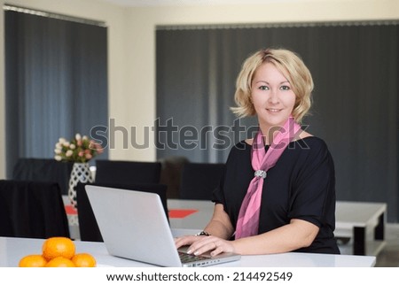 Blonde woman in black dress is working on a laptop in the bench top.