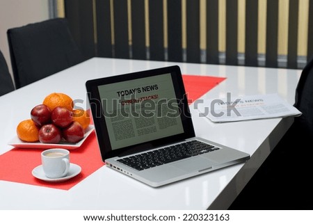 Laptop open on a todays news page on a table showing a cyber attacks article.