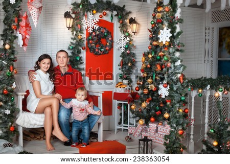 Young family sitting in the decoration of the room near the Christmas tree