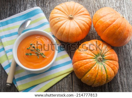pumpkin soup puree and small pumpkins on wooden table