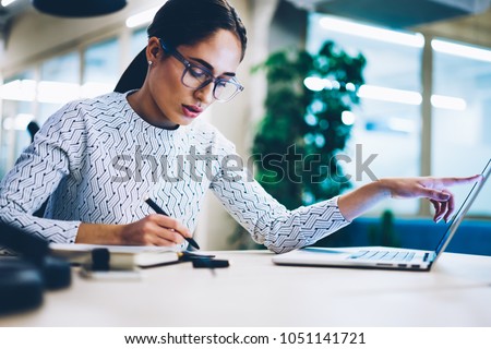 Pensive business woman noting idea for startup planning from web page on laptop computer,professional administrative manager making accountings of income using app on netbook in office interior Foto d'archivio © 