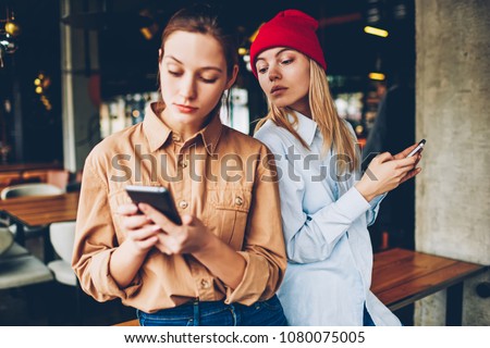 Hipster blogger spying online chat on smartphone of friend.Addicted best friends in casual outfit ignoring live communicating while spending leisure time in social networks on modern cellulars Stock fotó © 